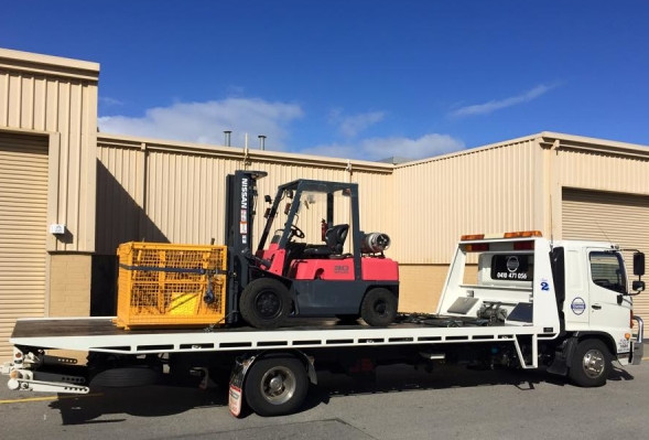 A Nissan forklift and yellow storage cage loaded onto a white tilt tray towing truck for transport.