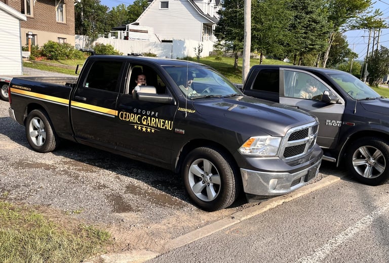 A black Groupe Cedric Garneau Ram 1500 work truck parked on a gravel lot.