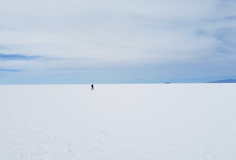 Monsieur Rêve traverse l'immense étendue blanche du Salar d'Uyuni sous un ciel bleu.