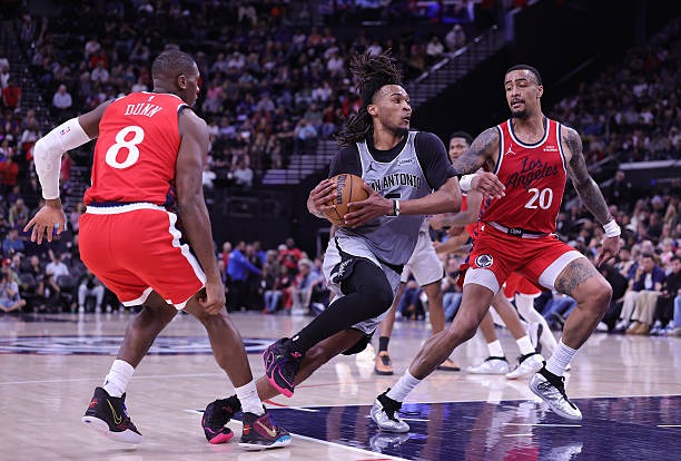 Stephon Castle of the Spurs controls the ball against Kris Dunn and John Collins of the Clippers