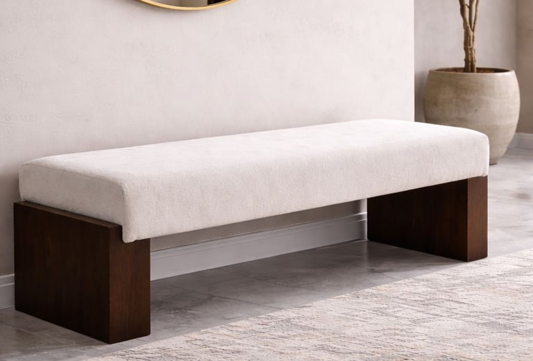 Ivory upholstered bench with dark wood base styled under a round mirror in a minimalist entryway with a neutral rug.