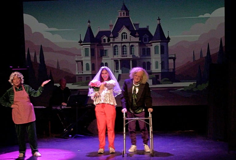 A theatrical comedy performance on stage featuring actors in costumes with a haunted mansion backdrop.