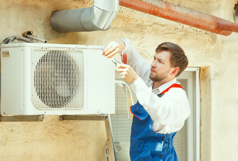 a man in overalls and overalls is fixing a heat pump