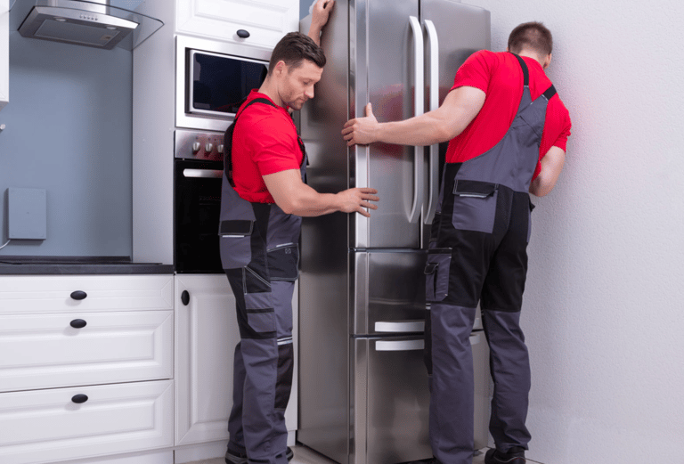 two men in red shirts and overalls standing in front of a refrigerator