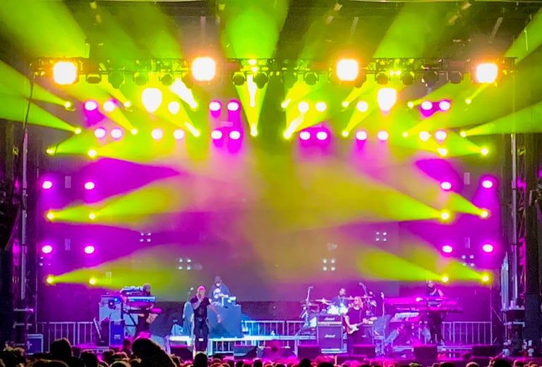 Lots of LED moving head fixtures on an outdoor stage at a music festival.