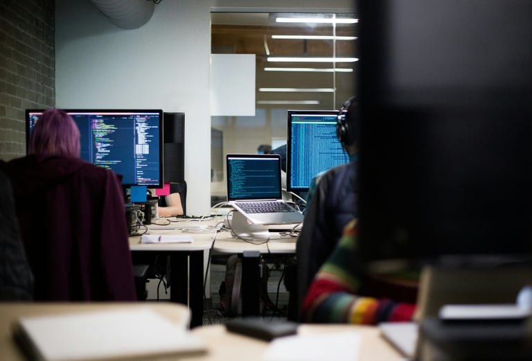 People at desks with code on monitors