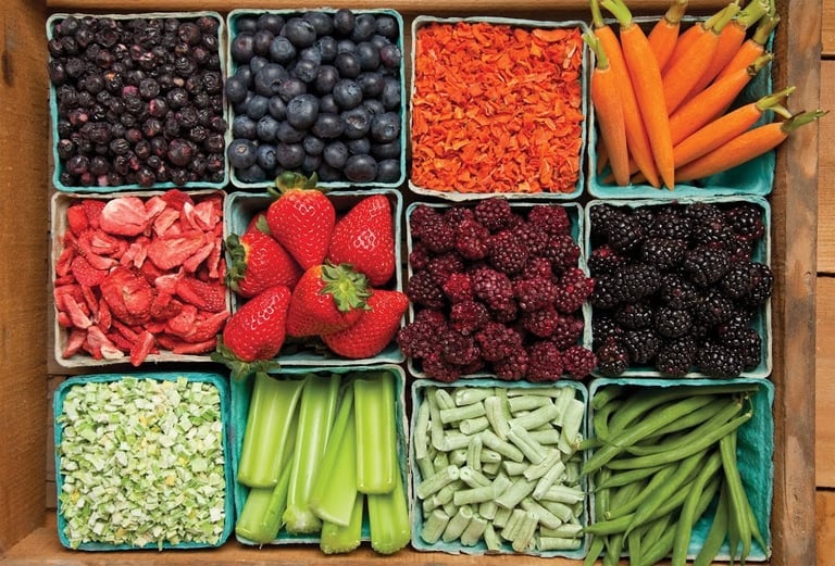 Variety of fresh and dried fruits and vegetables like berries, carrots, and beans in a wooden crate.