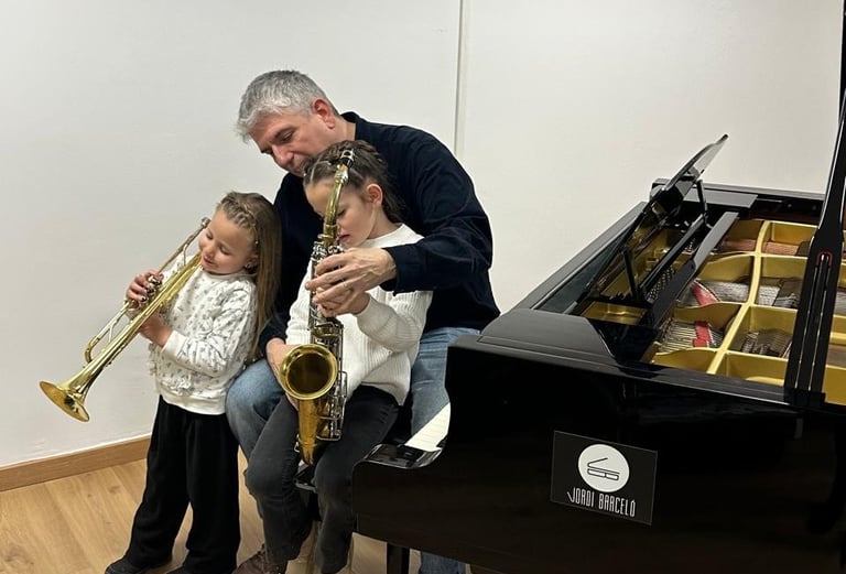 two little girls playing with a trumpet and saxophone infront a baby piano and music teacher
