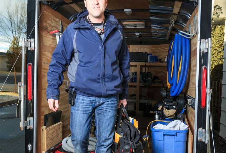 a man in a blue jacket is standing in front of a moving truck
