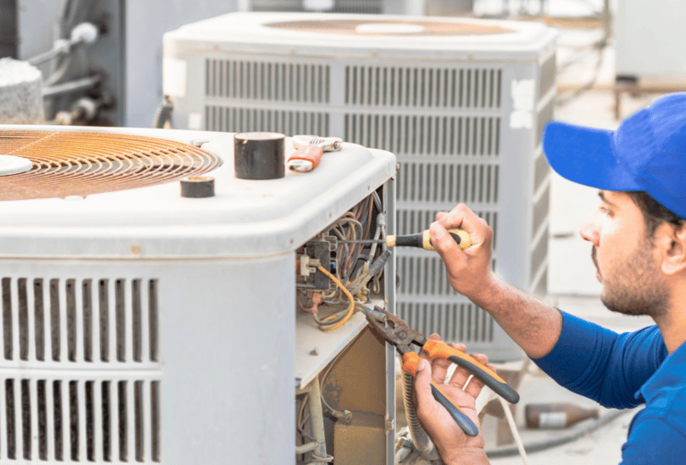 a man in a blue shirt is working on a large air conditioner