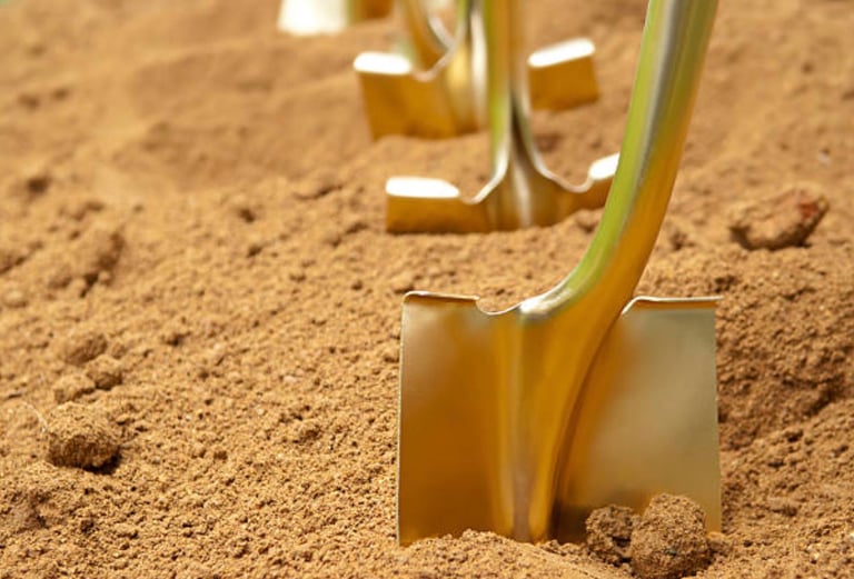 gold spades lined up in tanned earth waiting for the internment proceedings to start