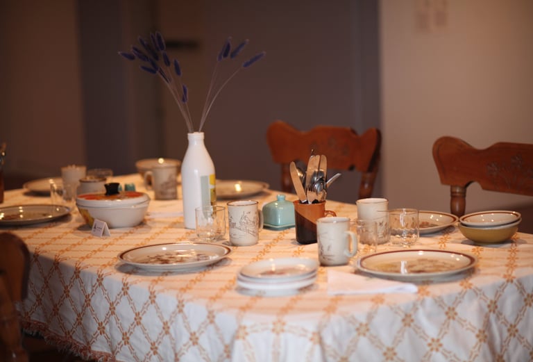 An empty table with recycled kitchenware sits in a gallery playing sounds of people cooking