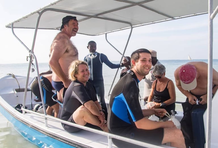 Smiling divers in wetsuits on a boat preparing for a scuba diving excursion in the ocean.