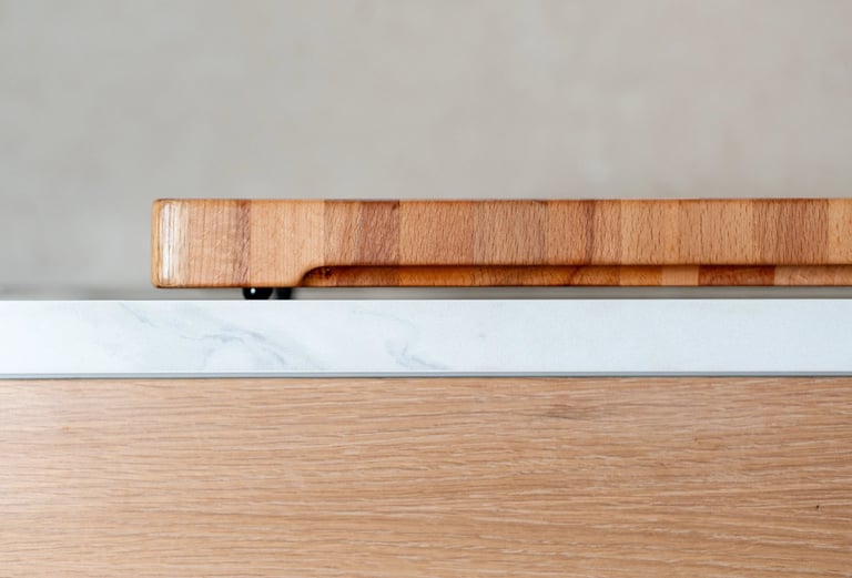 Side view of a thick wooden chopping board resting on a marble worktop