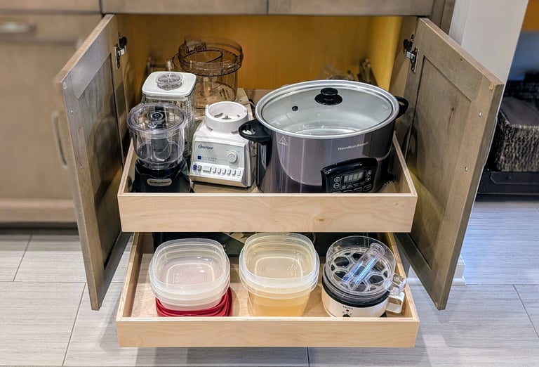 A kitchen cabinet with custom slide out shelves that are fully loaded with kitchen items.