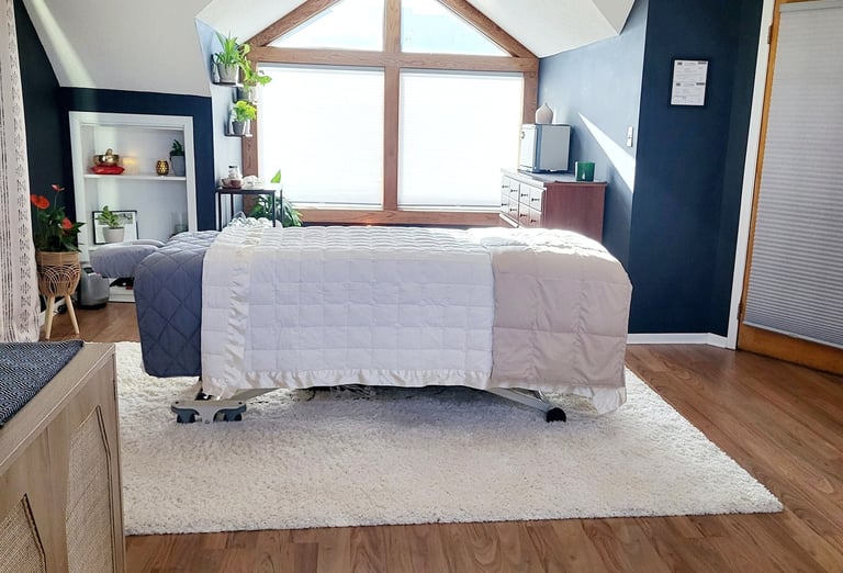 A professional massage table in a cozy room filled with plants and natural light