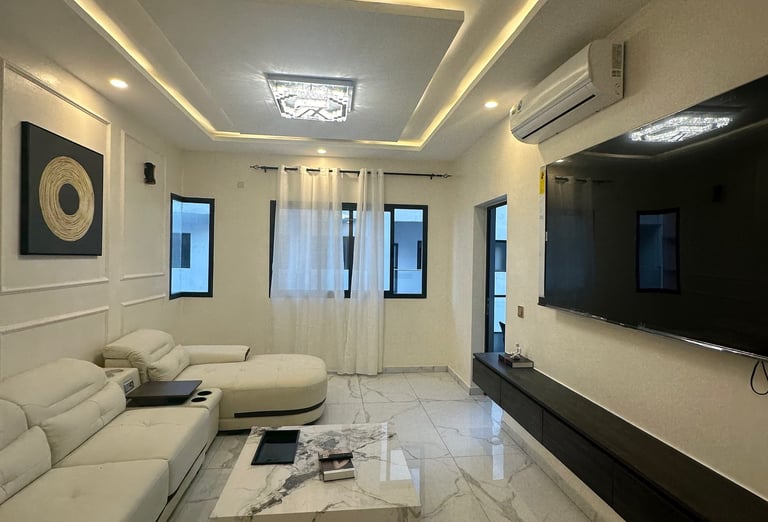 Salon lumineux avec canapé blanc et finitions murales élégantes à Abidjan