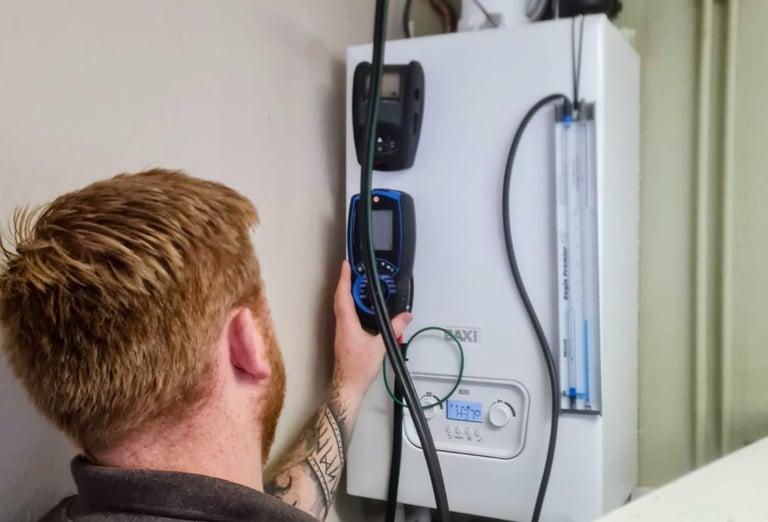 A heating engineer performs a gas boiler service and safety inspection using a digital flue gas analyzer.