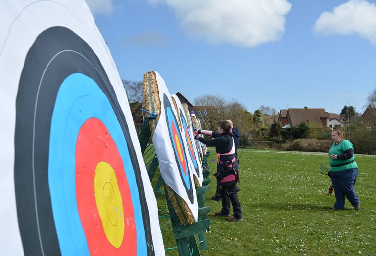 a man and woman are standing in front of an archery target