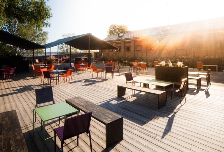 a wooden deck with chairs and tables in the sun