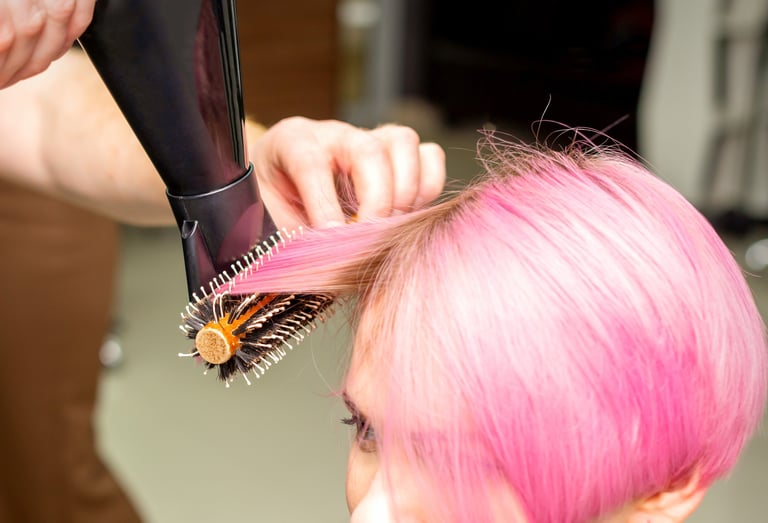 Hair model with vibrant pink full-head color during blow-dry.