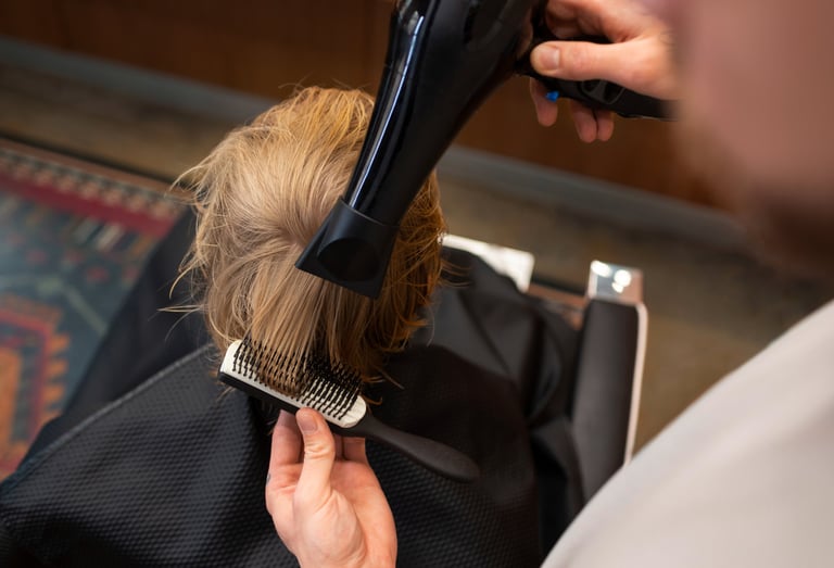 a woman is blow drying her hair in a salon
