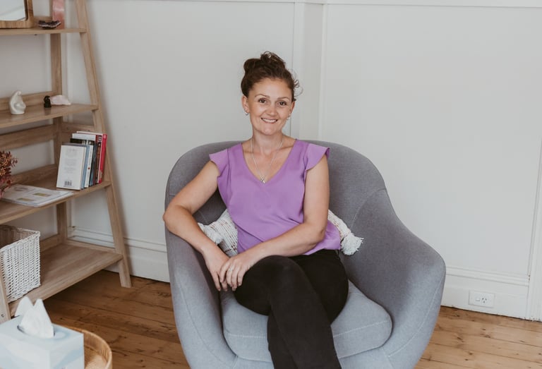 a woman sitting in a chair with a bookcase