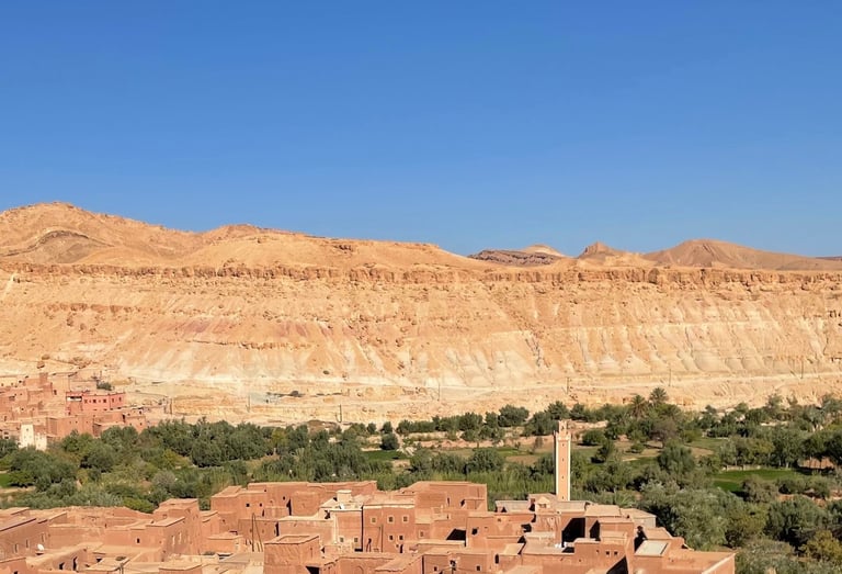 earthen village in the Ounila valley (Morocco), with mosque, fields and mountains in the background
