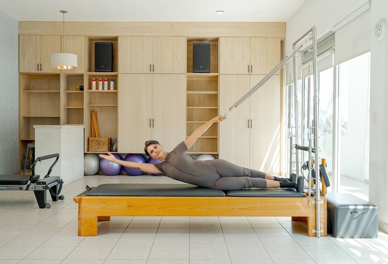 Woman performing a side-lying torso stretch using the springs of a Cadillac Pilates unit.