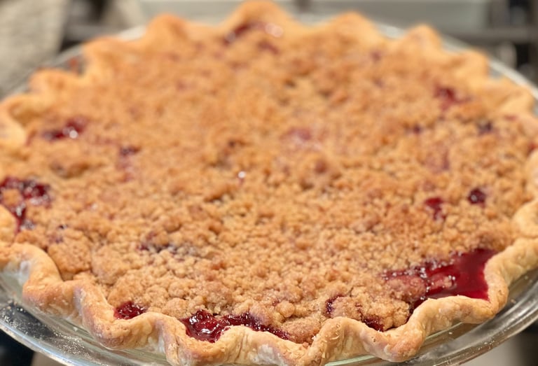 Freshly baked cherry pie with a golden brown streusel crumble topping and fluted buttery crust.