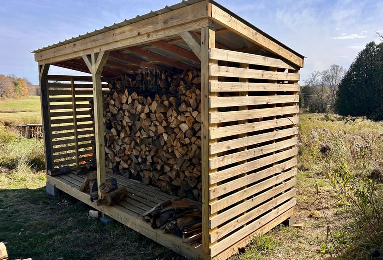 a wooden storage shed with logs stacked on top of it