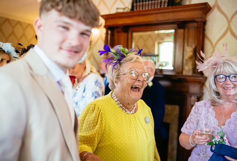 Guests share laughter at a wedding reception in Decourcey’s Manor, Cardiff, full of colour, joy and character.