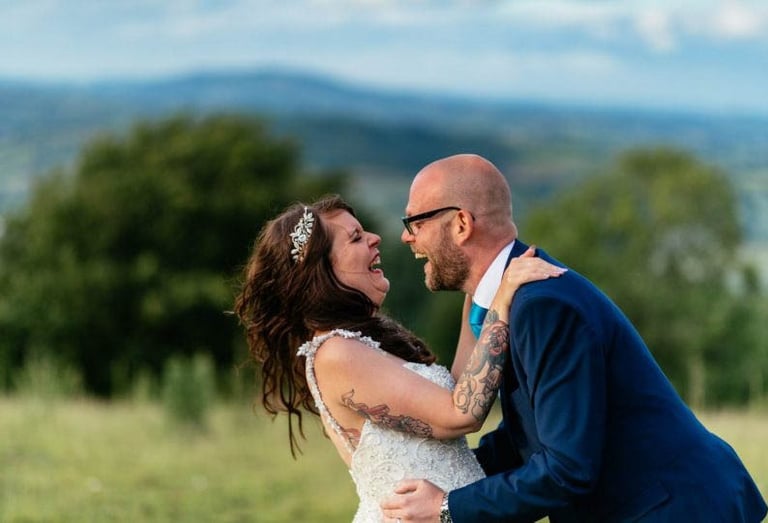 Bride and groom laughing outdoors at South Wales countryside wedding, captured by photographer Owen Mathias