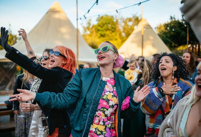 Wedding guests dancing and singing at Ceridwen Centre outdoor wedding in South Wales, captured by photographer Owen Mathias