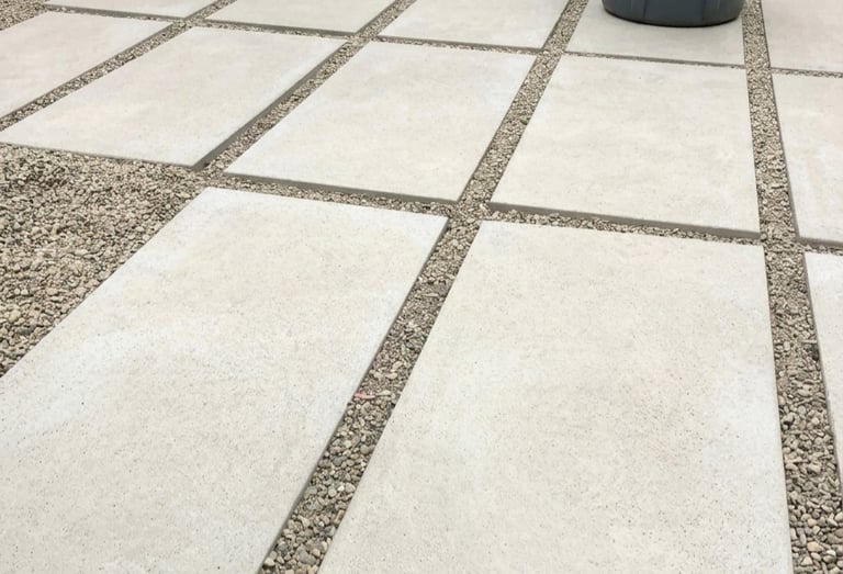 Modern backyard landscaping featuring large concrete pavers and pea gravel, creating a stylish and f