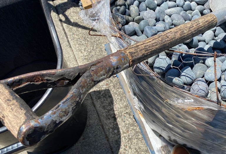 Landscaping San Francisco project showing a worker using a metal garden shovel to place black Mexica