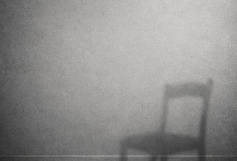Minimalist black and white image of a chair casting a shadow