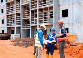 Ouvriers de chantier en casques révisant des plans devant un bâtiment à étages au cameroun