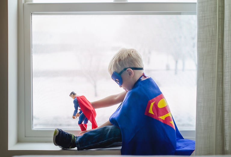 Super hero kid playing with a super hero toy
