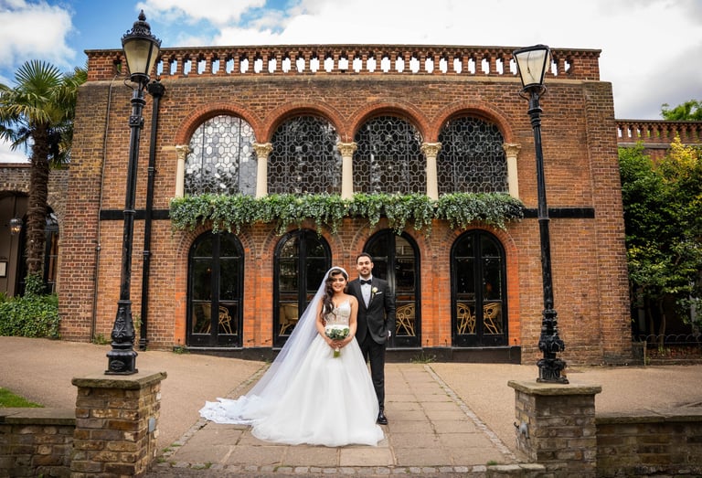 Bride and groom standing in front of a historic brick building, captured by Fred Art Studio.