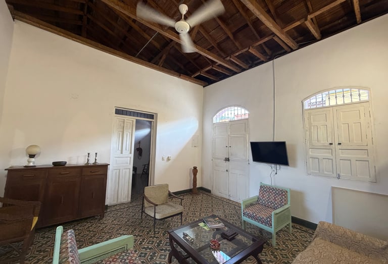 Rustic living room with high vaulted wooden ceilings, patterned tile floors, and colonial-style furniture.