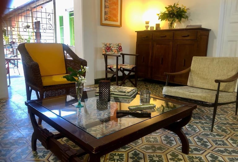 Rustic living room with vintage chairs, glass coffee table, and patterned tile floor.