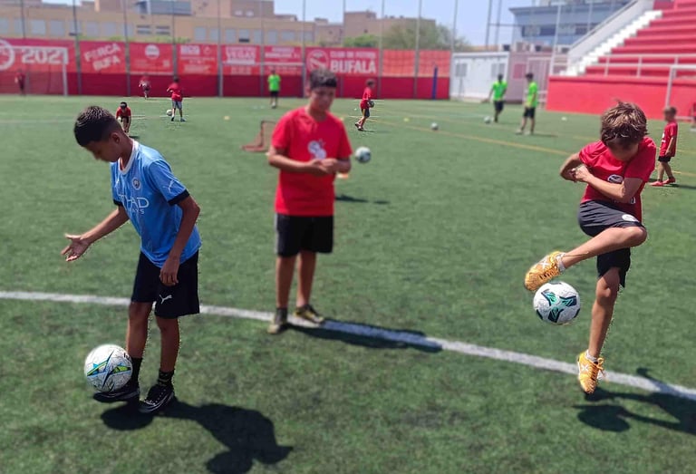 Niños aprendiendo trucos de freestyle fútbol como la vuelta al mundo en una masterclass en Barcelona