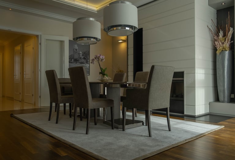 Elegant modern dining room featuring high-back upholstered chairs, a contemporary table, and pendant lighting.