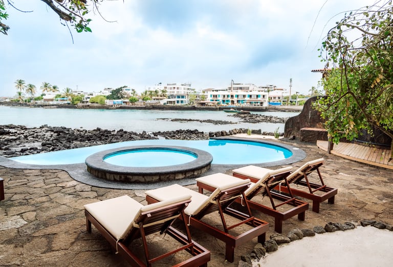 Oceanfront swimming pool and sun loungers at Villa Escalesia Galápagos, overlooking the rocky coastl