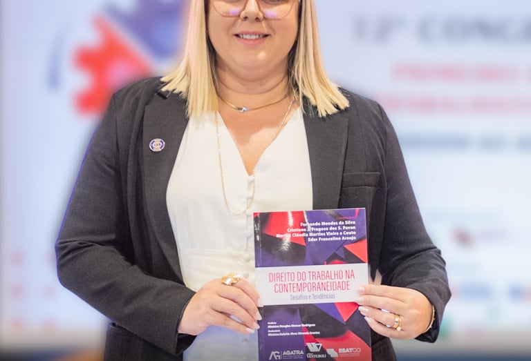 Uma mulher loira de terno e óculos segurando um livro.