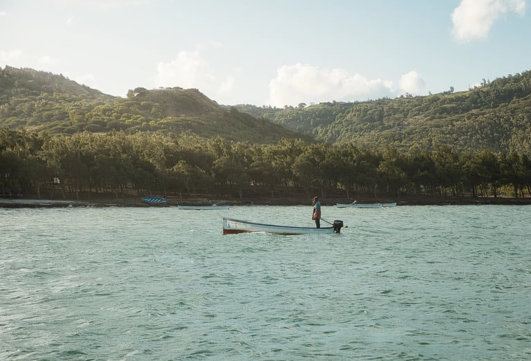 Fisherman in Rodrigues standing on his moving boat with the beautiful backdrop of the hills