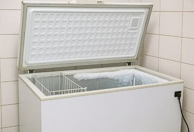 Freezer horizontal branco com tampa aberta e acúmulo de gelo, manutenção em Curitiba pela Veralice Refrigeração.