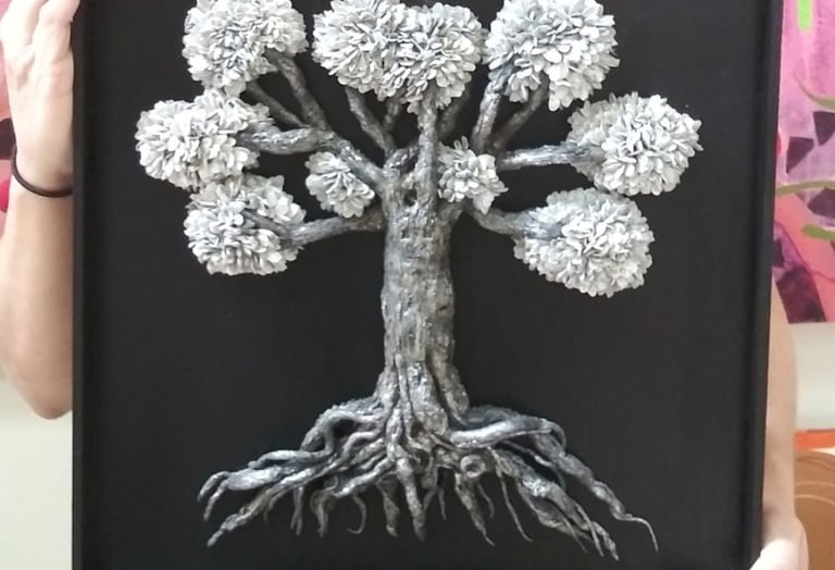 a woman holding a framed picture of a tree