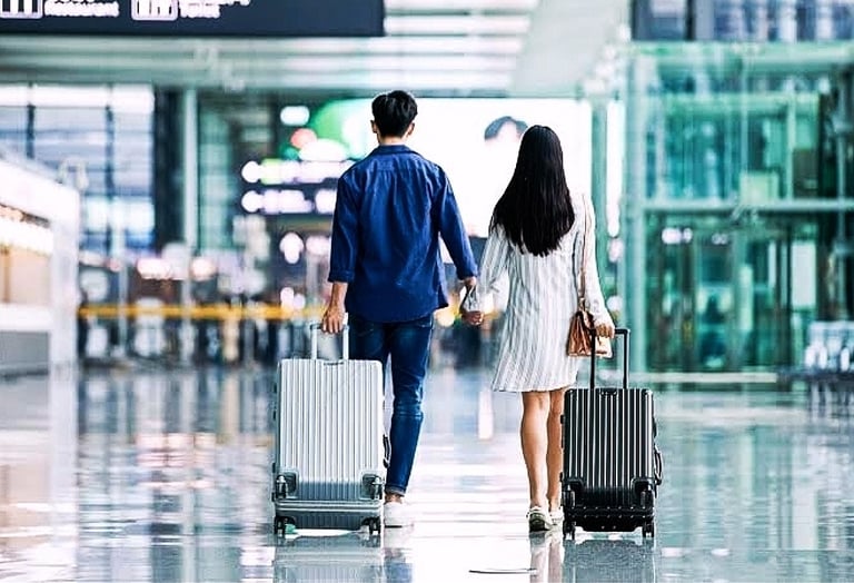 a man and woman holding hands while walking through an airport
